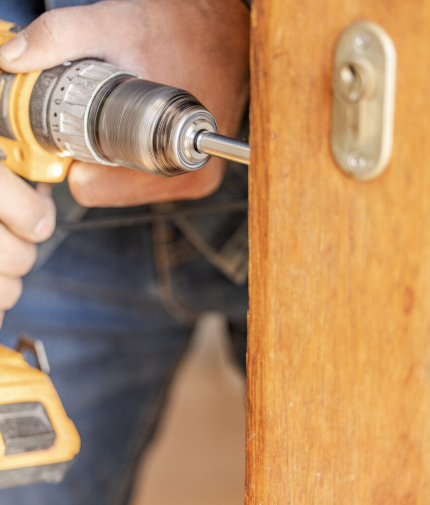 Locksmith hands, maintenance and handyman with construction and fixing, change door locks with tool